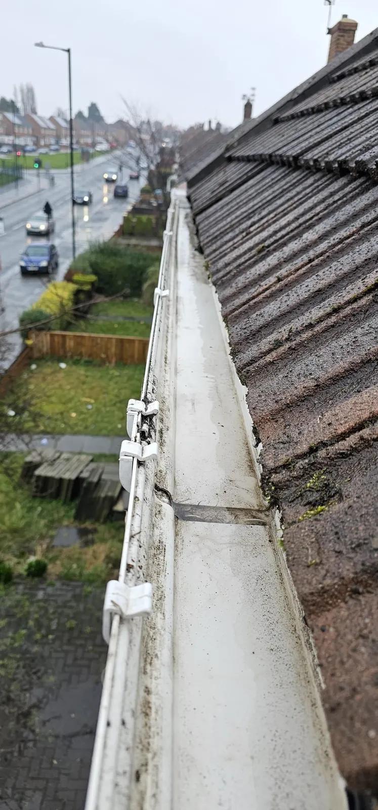 Cleared white gutter along the edge of a pitched tiled roof